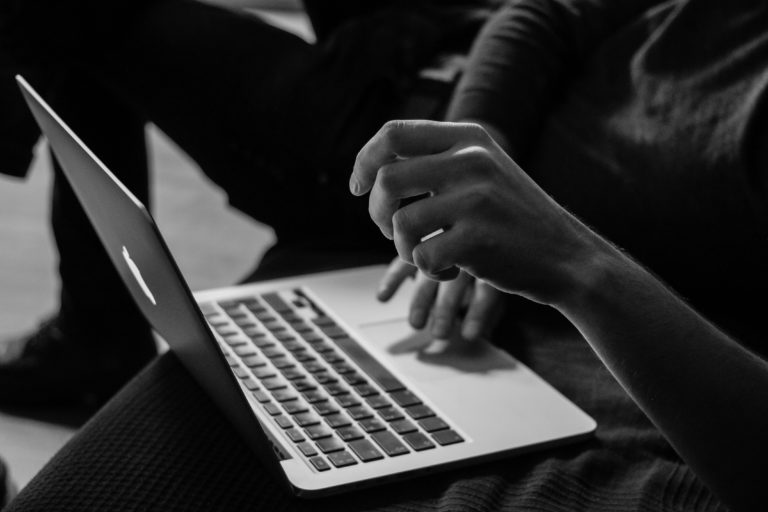 Black and white photo of a man sitting with a laptop working